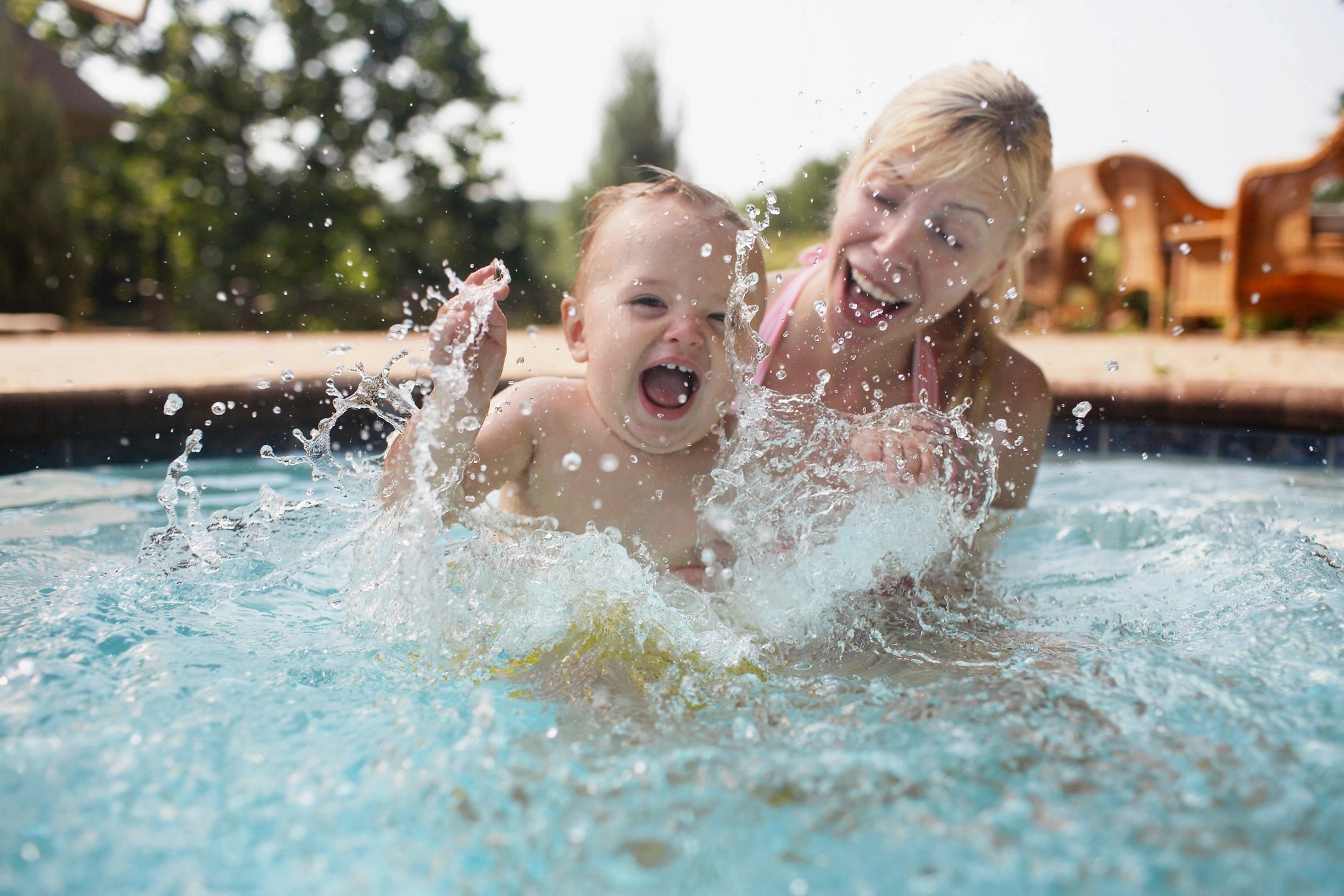 Happy children splashing in a backyard swimming pool