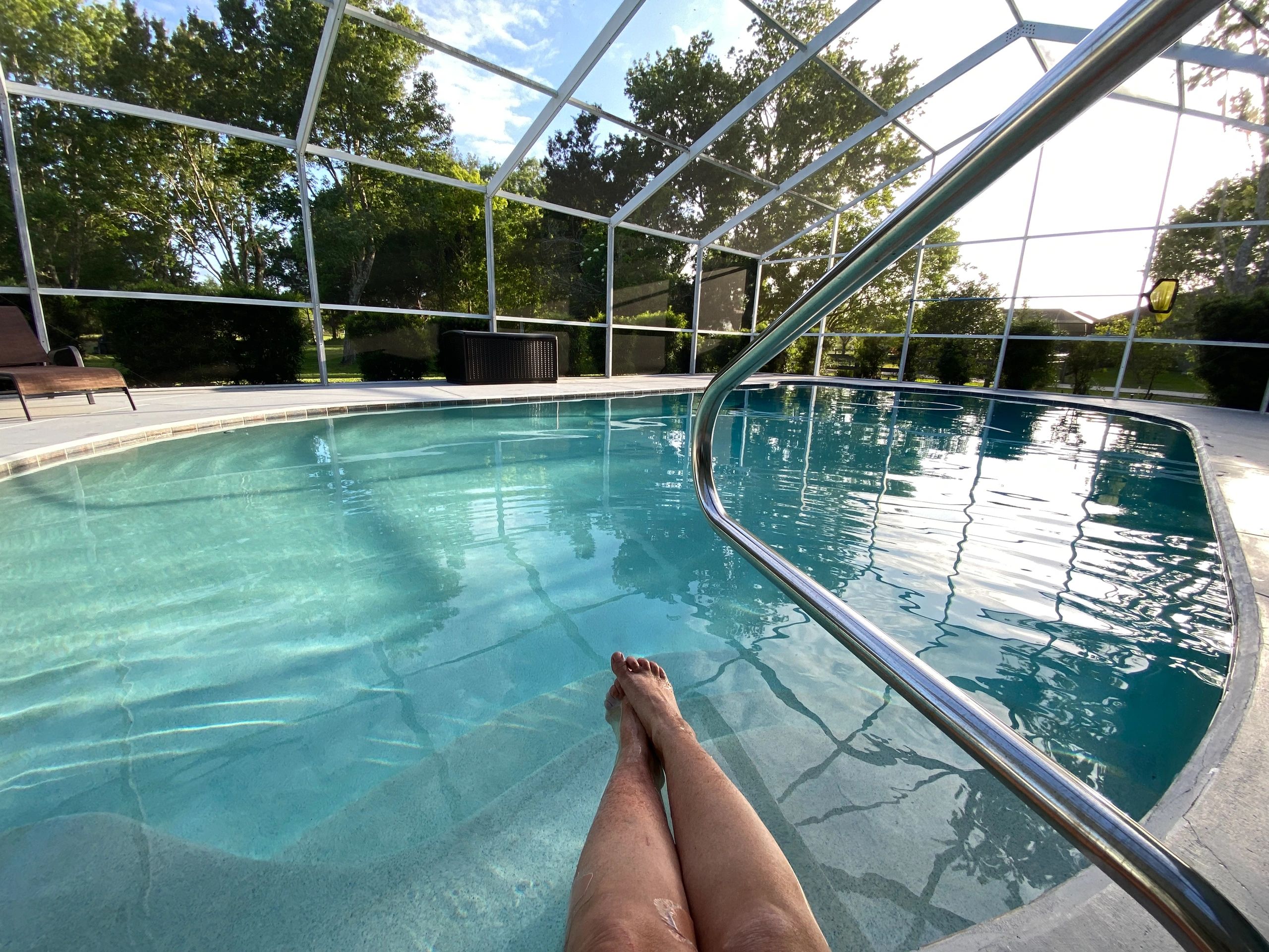 Crystal-clear swimming pool inside a screened enclosure with turquoise water